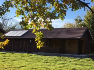 Photo of outside of toilet and shower block on campsite showing autumn leaves and solar panels