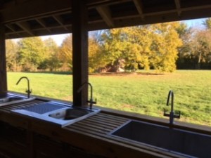 Photo looking out from washing up area to campsite in autumn colours