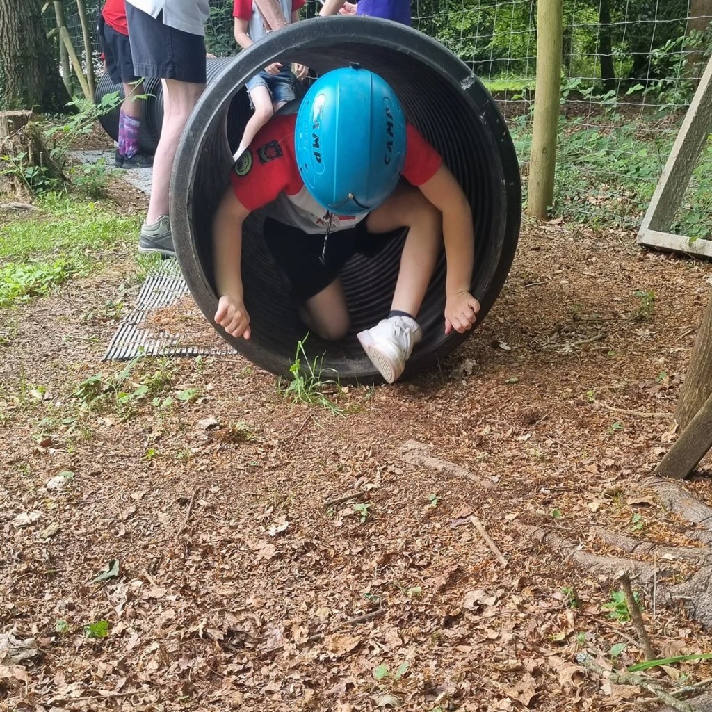 A Rainbow crawls through a tunnel wearing a helmet