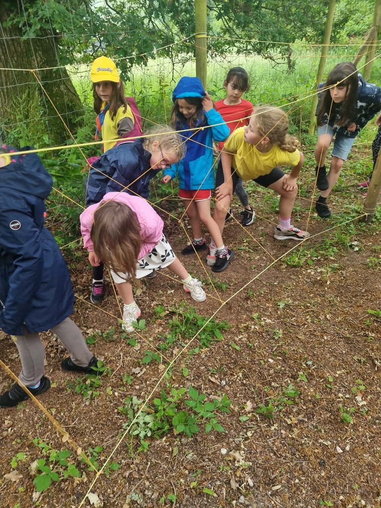 Brownies and Rainbows try to get through a string 'spiders web' at an outdoor activity