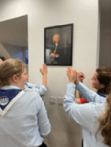 Rangers in front of a painting of Bach, laughing and holding their hands prayer style