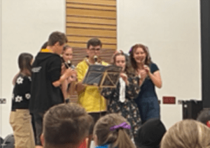 A group of young people playing recorders around a music stand