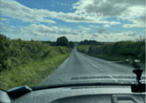 A bright and sunny view through a car windscreen on the journey to Somerset surrounded by green hedgerows and fields