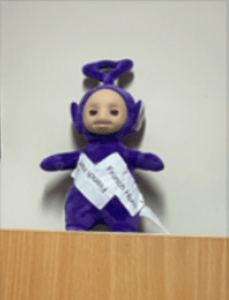 The purple Tinky Winky Tellytubbies character, with labels stuck to it saying 'French Horns'