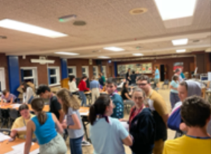 A group of young people in a hall mixing and taking part in activities