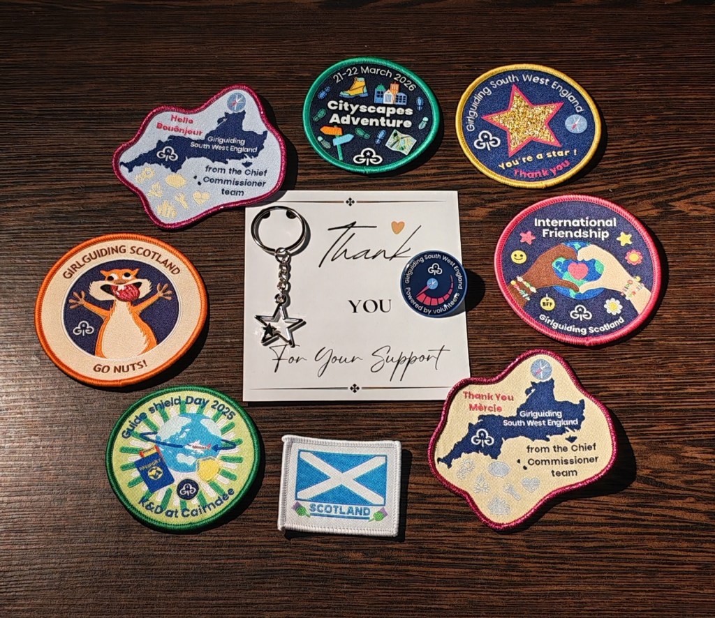 A thank you note and badge surrounded by badges our Girlguiding volunteer collected during her Cityscape experience 
