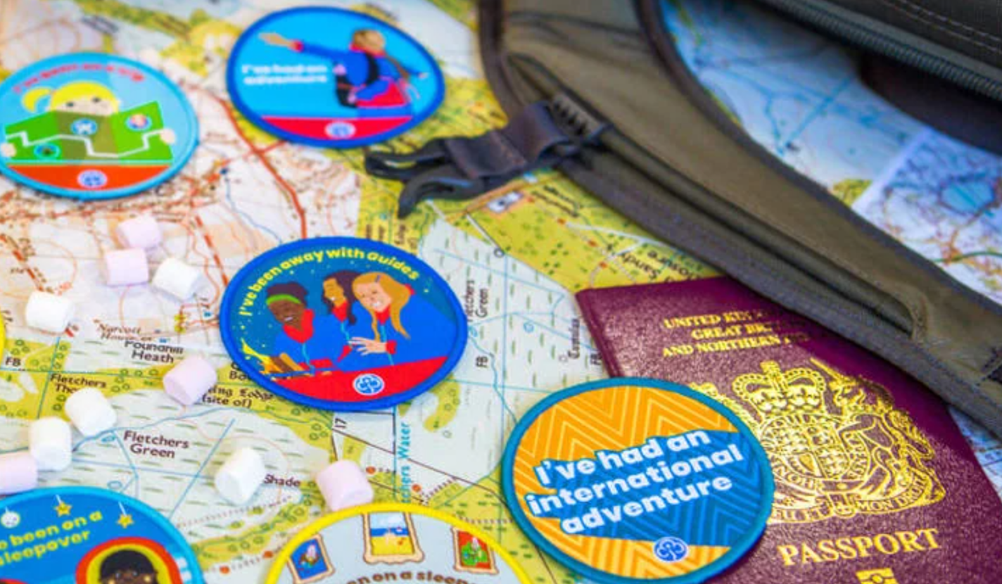 A selection of Girlguiding international badges sitting on a map